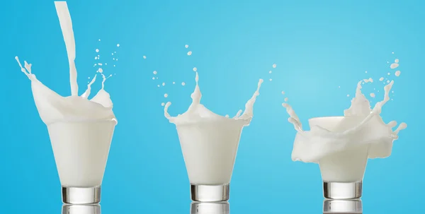 Splash van melk van het glas op een blauwe achtergrond — Stockfoto