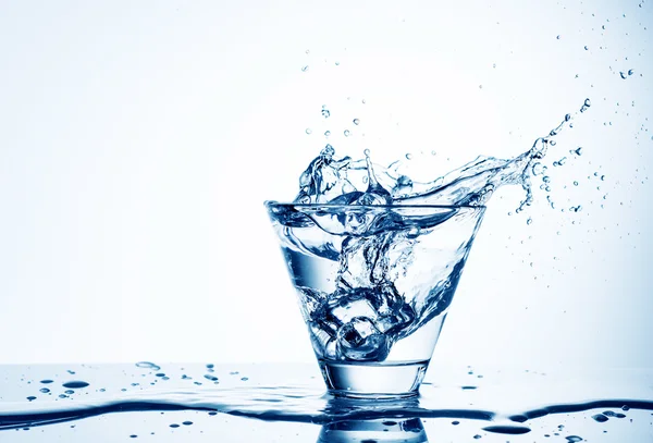 Ice cubes splashing into glass of water, isolated on white — Stock Photo, Image