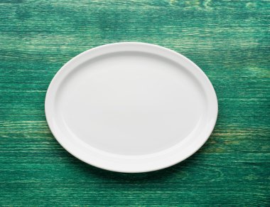 Ahşap yeşil masada boş beyaz tabak