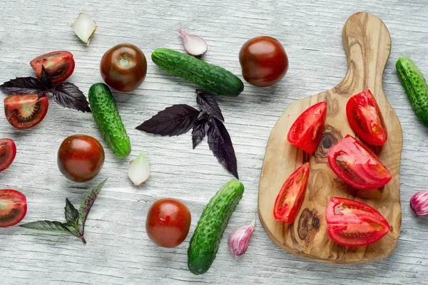 Tomater med basilika på träbord bakgrund. Mat sammansättning. Ovanifrån — Stockfoto