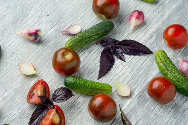 Domates, otlar, soğan ve salatalık Beyaz ahşap zemin üzerinde