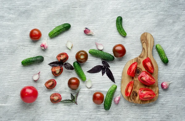 Kruiden, uien, tomaten en komkommers over witte houten achtergrond — Stockfoto