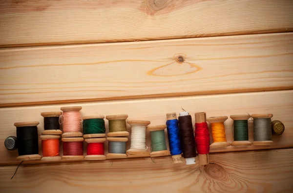 Sewing kit. Scissors, bobbins with thread and needles on the old wooden background — Stock Photo, Image