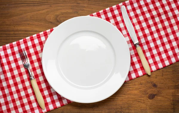 나무 탁자 위에 포크와 칼을 얹은 빈 접시. — 스톡 사진