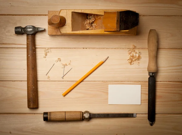 Инструменты столярного дела на фоне деревянного стола с визитной карточкой — стоковое фото