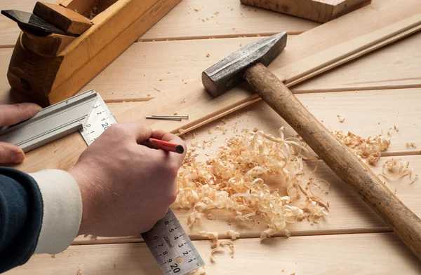 Herramientas de carpintero, martillo, medidor, clavos, virutas y plano sobre la mesa de madera —  Fotos de Stock