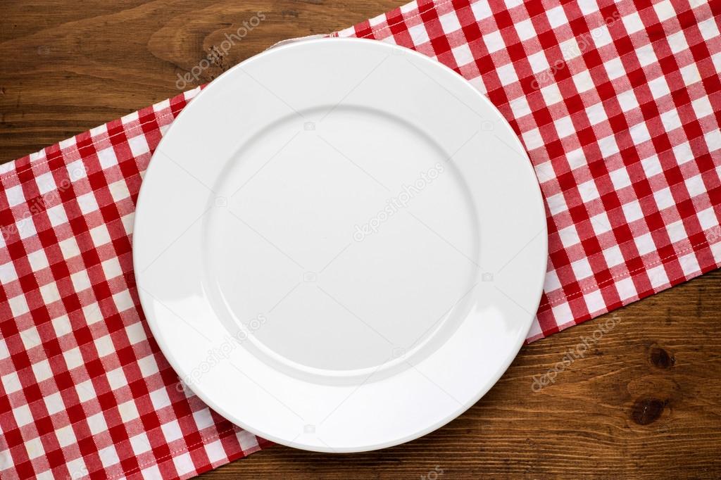 Empty plate on wooden tabletop with tablecloth