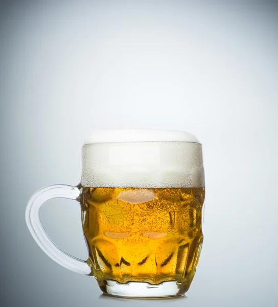 Caneca de cerveja fresca e tampão de espuma no fundo branco — Fotografia de Stock