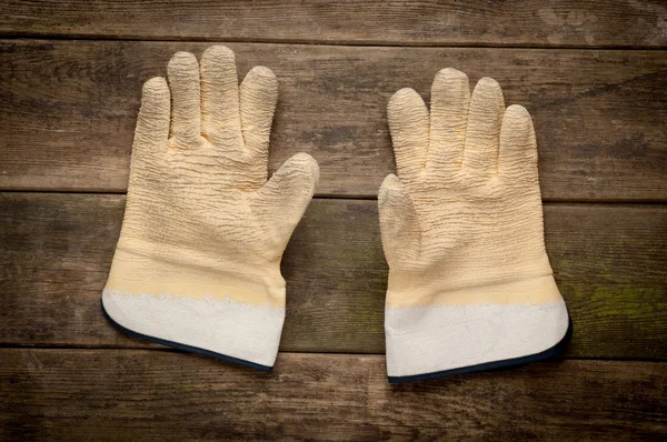 Pair work gloves lying on planks of wood — Stock Photo, Image