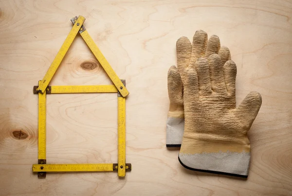 House concept with yellow meter and working gloves on wooden — Stock Photo, Image