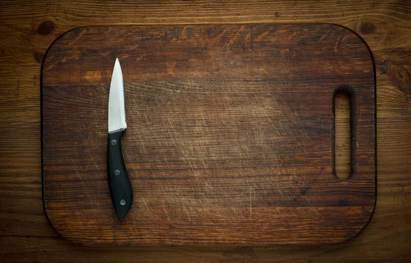 Cutting breadboard and knife overwooden background — Stock Photo, Image