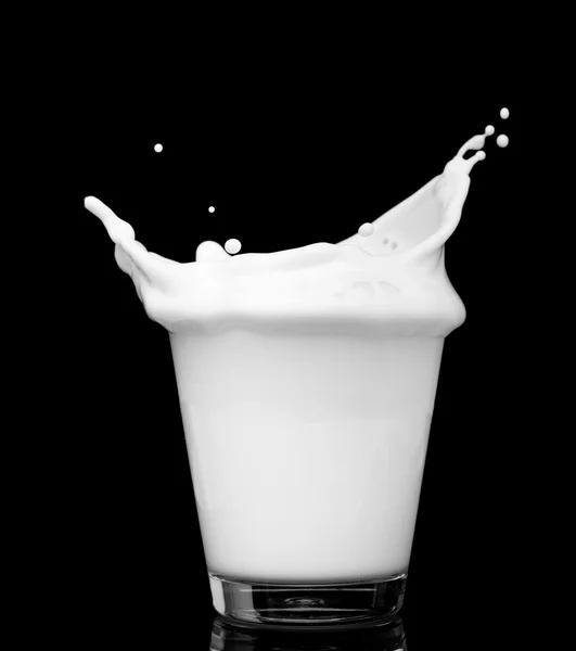 Splashind vaso de leche sobre fondo negro —  Fotos de Stock