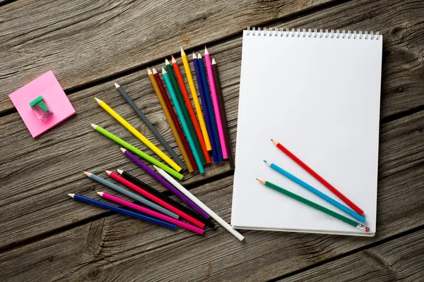 Espacio de trabajo con lápices de colores y cuaderno de vieja madera — Foto de Stock