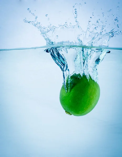 Fresh lime falling into water, on white — Stock Photo, Image