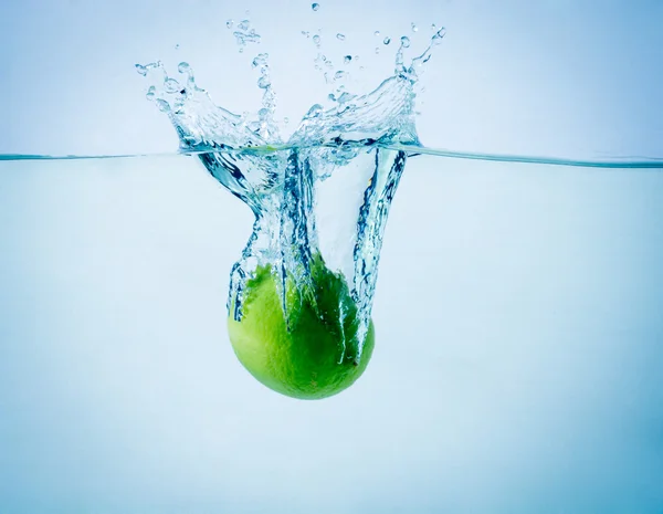 Alta velocità congelare colpo di azione di un lime che spruzza in acqua su priorità bassa bianca — Foto Stock