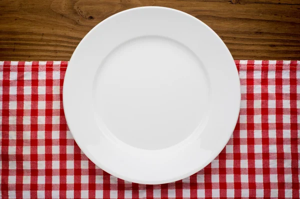 Empty white plate on wooden over red grunge background — Stock Photo, Image