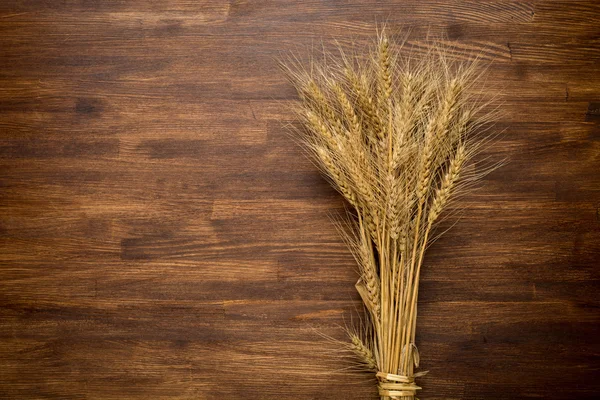 Espigas de trigo na mesa de madeira. Feixe de trigo ao longo de madeira. Conceito de colheita — Fotografia de Stock