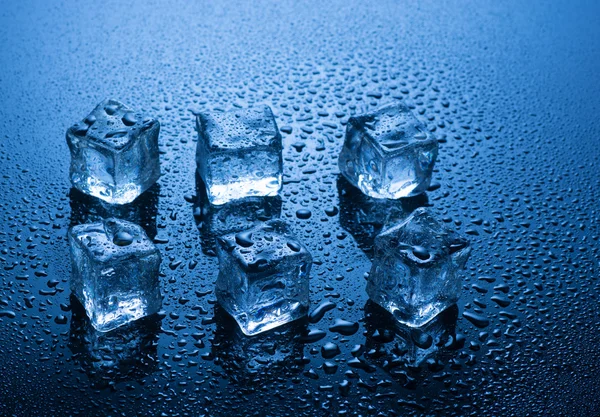 Cubos de gelo com gotas de água no fundo azul — Fotografia de Stock