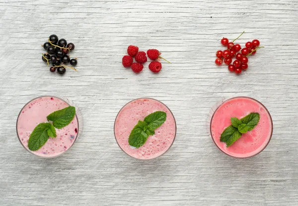 Leche fresca, grosella, frambuesa y rojo grosella bebidas en la mesa de wodeen, surtido de cócteles de proteínas con frutas frescas —  Fotos de Stock