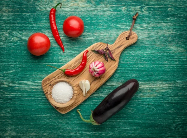 Tomatos, Red chili peppers, garlic, basil  and salt over a wooden background — Stock Photo, Image