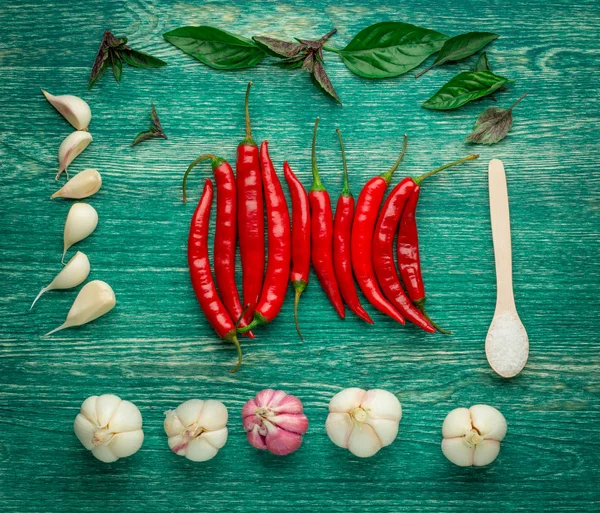 Red hot chili peppers with spice ingredients and salt over wooden background — Stockfoto