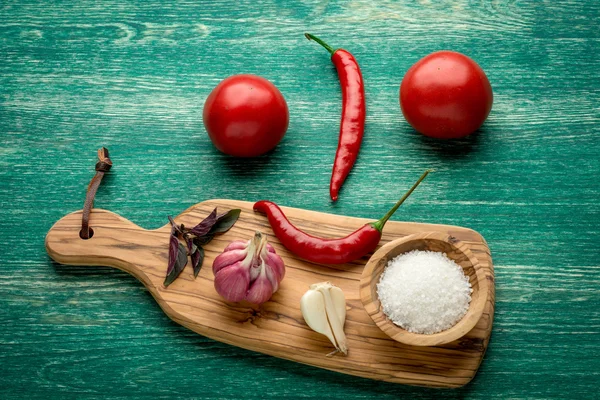 Tomatos, Red chili peppers, garlic, basil  and salt over a wooden background — Stockfoto