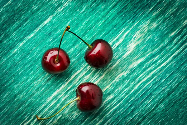 Cerejas na mesa de madeira com fundo macro gotas de água — Fotografia de Stock