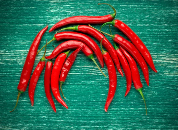 Pimientos rojos picantes sobre fondo de madera — Foto de Stock