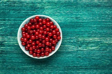 Kirazlar ahşap masada, su damlaları makro arka planda.