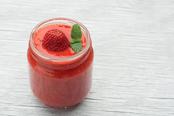 Copo de smoothie de morango em um fundo de madeira — Fotografia de Stock