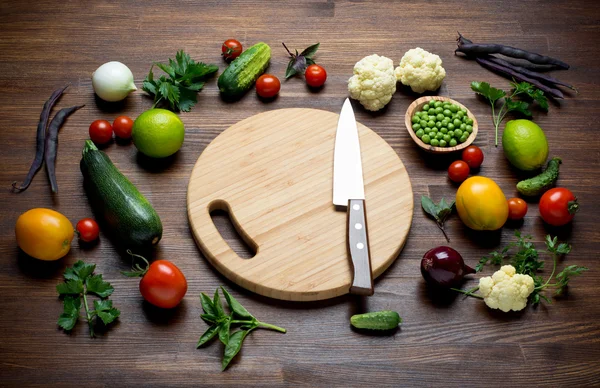 Verse biologische groenten op awooden tabel met snijplank en mes. — Stockfoto