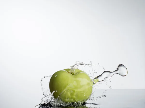 Green apple in splash of water on white background — Stock Photo, Image