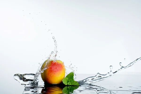 Melocotón en spray de agua. Melocotón jugoso con salpicadura sobre fondo blanco —  Fotos de Stock