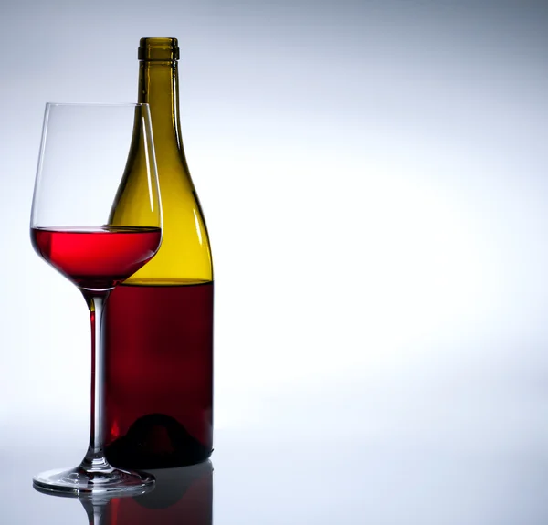 Botella de vino tinto y vidrio sobre fondo blanco — Foto de Stock