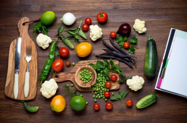 Sağlıklı gıda. Tarif kitabı ile ahşap masa üzerinde sebze ve otlar. Üstten Görünüm. 