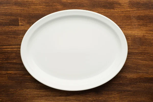 Empty white plate on wooden table — Stock Photo, Image