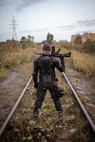 Un hombre con un rifle en uniforme se para con la espalda — Foto de Stock