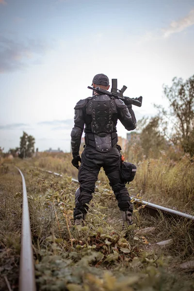 Un hombre con un rifle en uniforme se para con la espalda — Foto de Stock