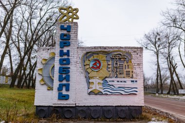 Çernobil, Ukrayna - Ağustos 2019 Ukraynaca Çernobil yazılı bir tabela. Anıtın üstünde sarı bir atom var. Yan tarafta bir sanayi fabrikası var. Çernobil girişi.