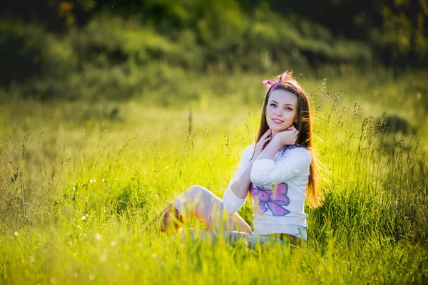 Молода красива дівчина сидить на траві і посміхається — стокове фото