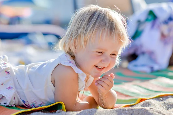 Küçük sarışın kız sahilde yalan söylüyor — Stok fotoğraf