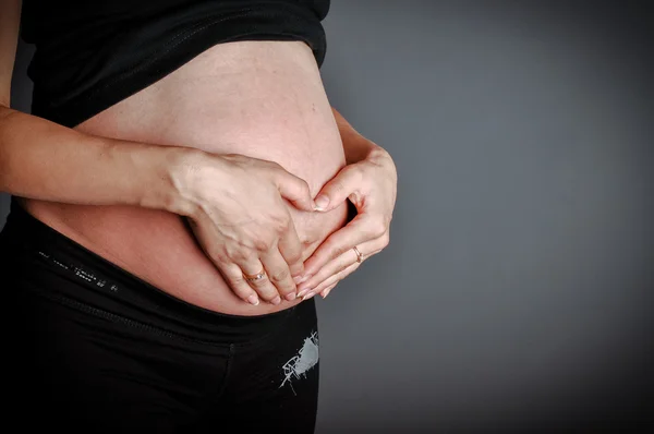 Mãos de membros da família segurando uma barriga de mulher grávida — Fotografia de Stock