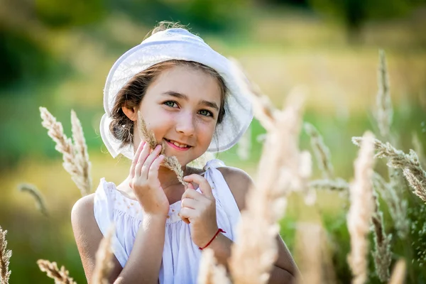 Hermosa niña con el pelo largo y rubio viaja en colorido campo amarillo —  Fotos de Stock