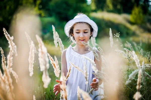 Hermosa niña con el pelo largo y rubio viaja en colorido campo amarillo — Foto de Stock