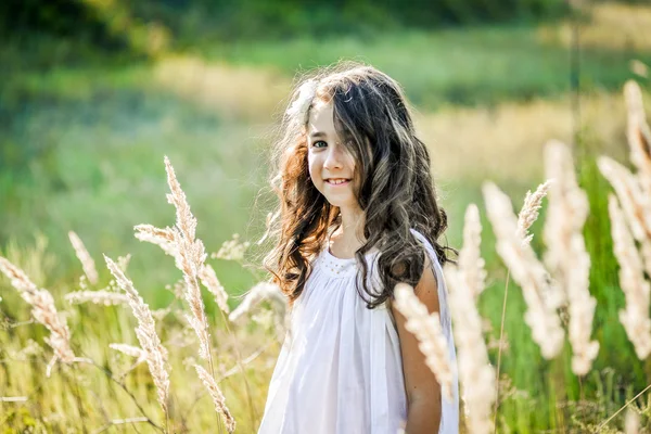Hermosa niña con el pelo largo y rubio viaja en colorido campo amarillo — Foto de Stock