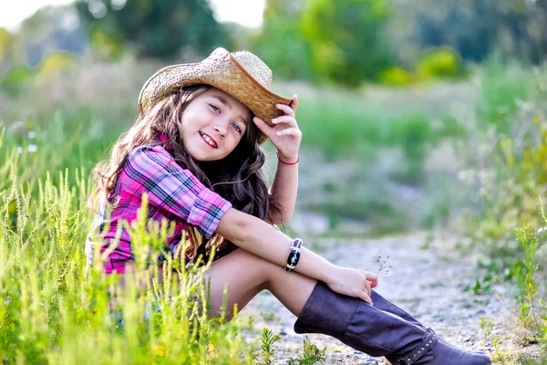카우보이 모자를 쓰고 필드에 앉아 어린 소녀 — 스톡 사진