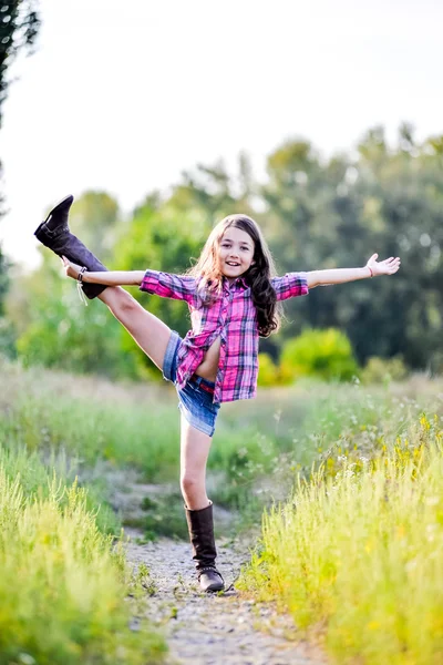 Niña sentada en un campo con un sombrero de vaquero — Foto de Stock