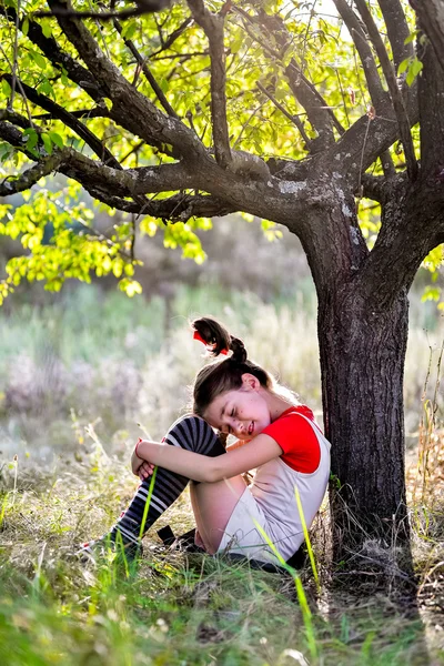 Menina triste com tranças sob a árvore — Fotografia de Stock