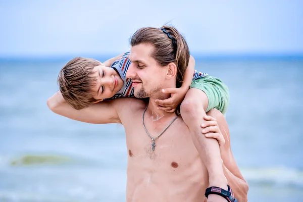 Padre e hijo jugando en la playa durante el día . — Foto de Stock