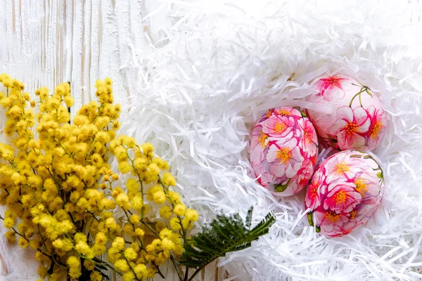 Прикрашені розфарбованими великодніми яйцями та квітами на світлому фоні — стокове фото
